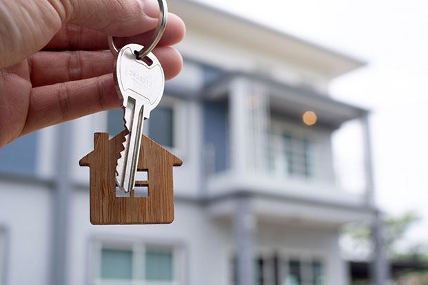 A home owner holds the key to their newly purchased property while assessing its windows