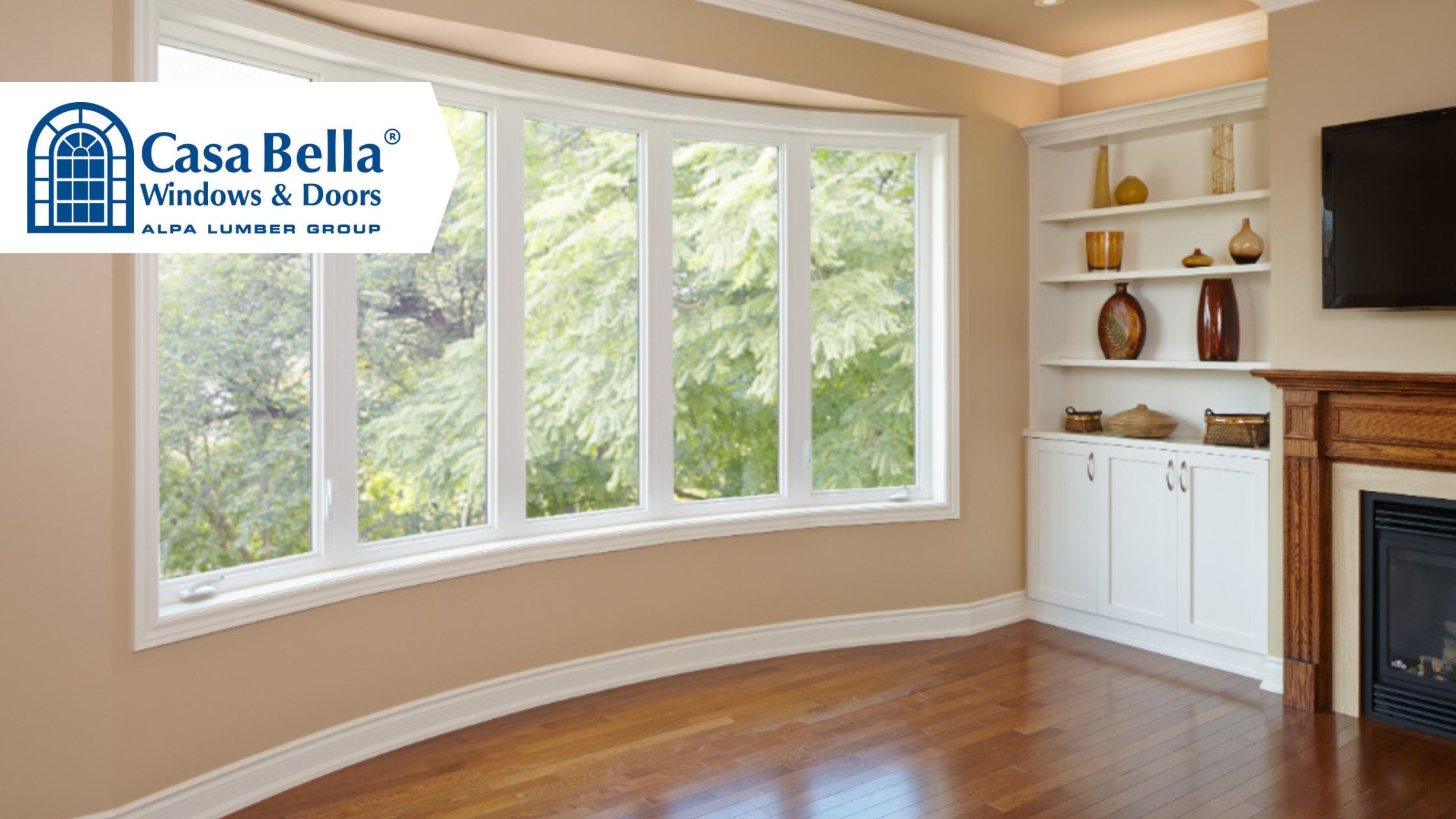 Bright living room with a large white bay window installation, hardwood floors, and built-in shelving, showcasing natural light and modern window design by Casa Bella Windows & Doors