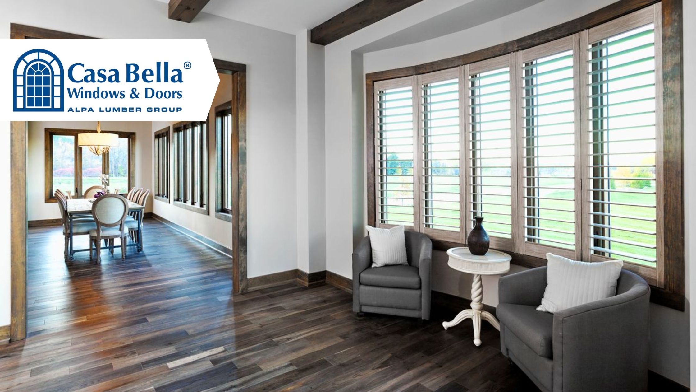 Modern home interior featuring large multi-panel windows with wood trim and shutters, bringing natural light into a dining and living space by Casa Bella Windows & Doors