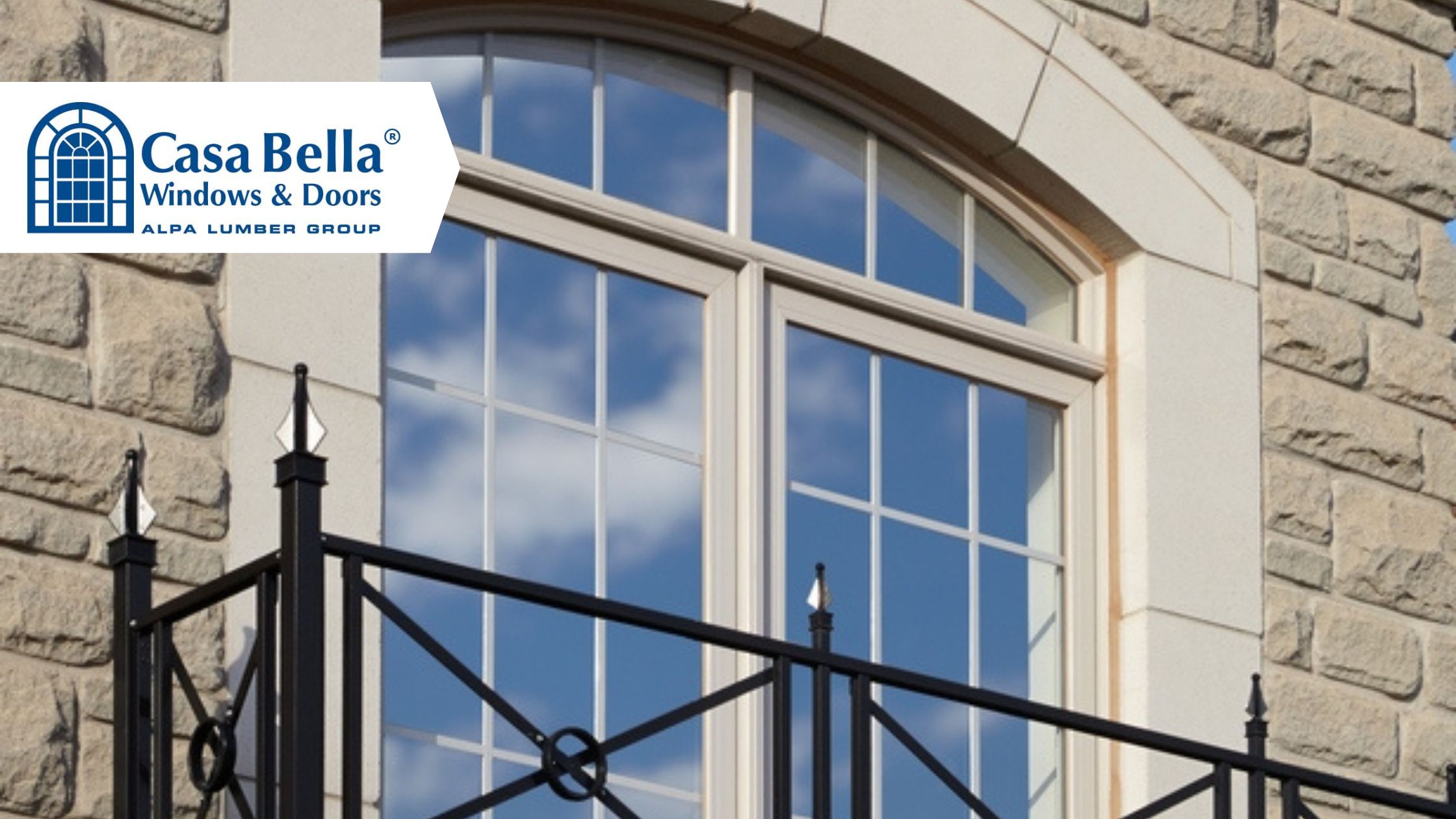 Large arched Casa Bella window with decorative grilles installed in a natural stone home exterior